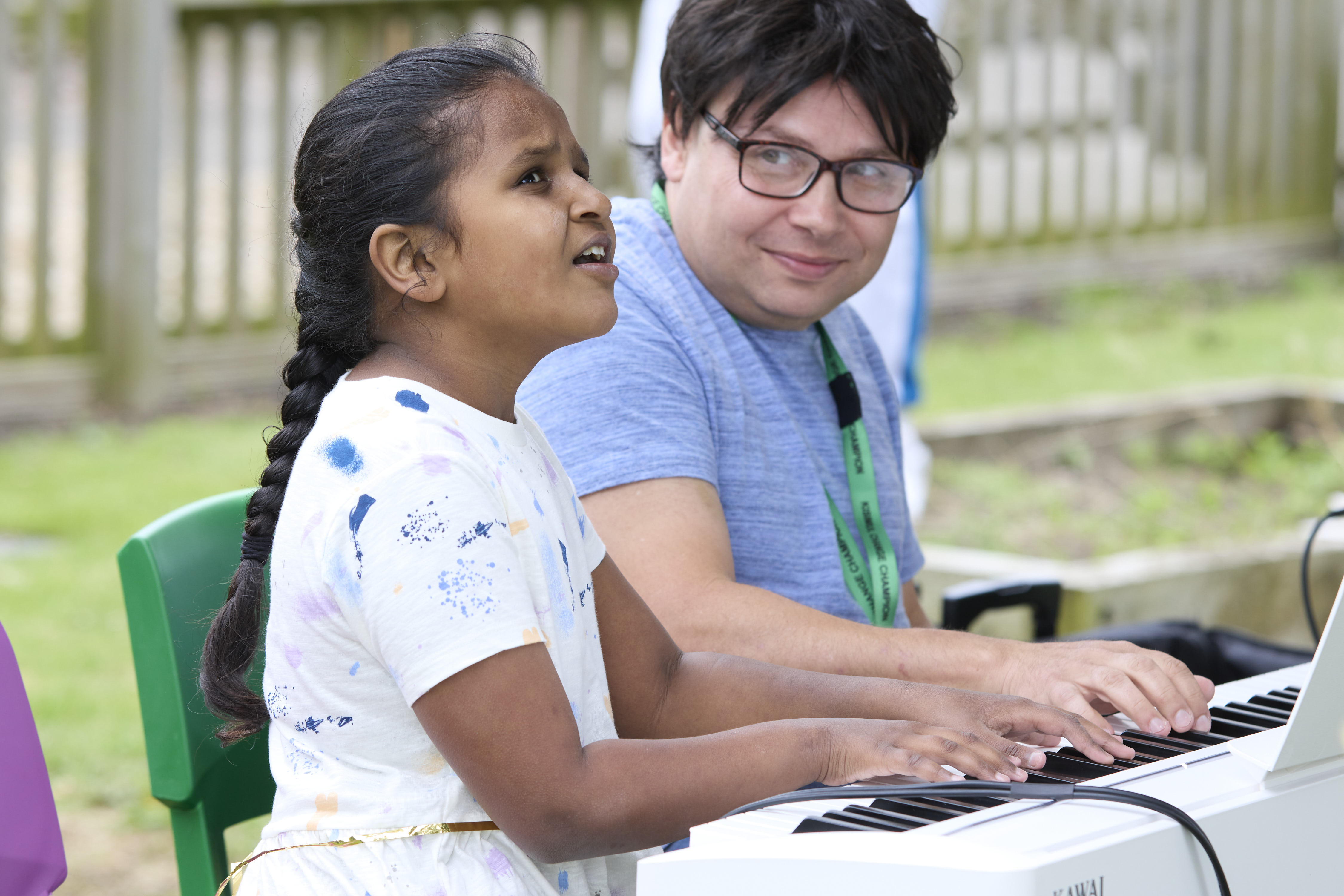 A girl singing while playing the piano with a man.